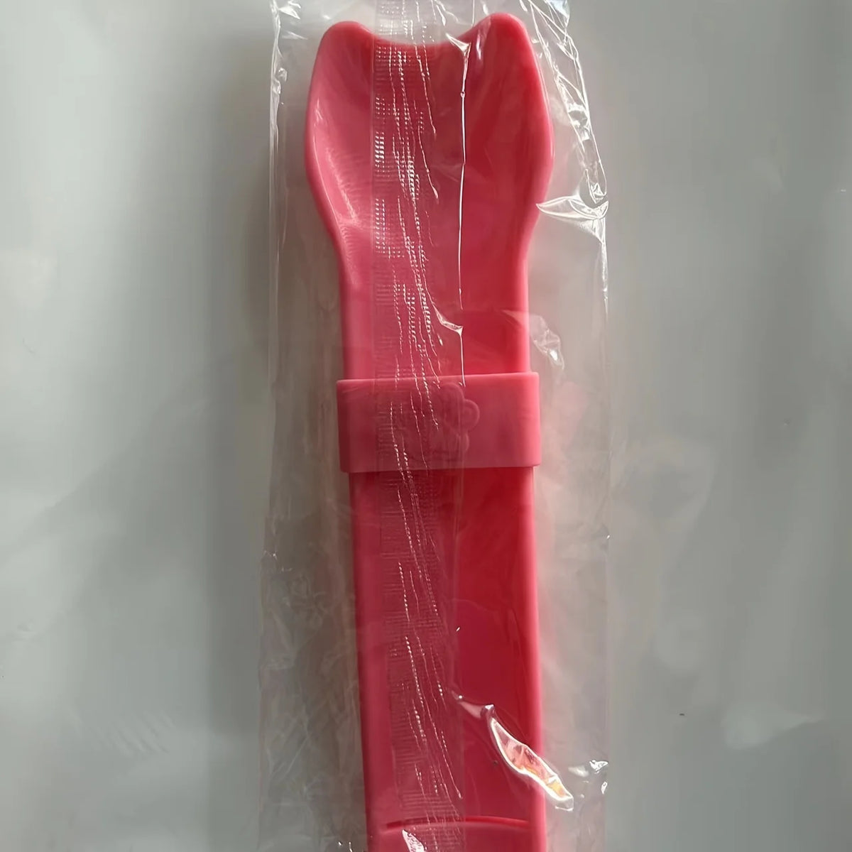 Cat Strip Squeeze Spoon holding pet food packet, designed for easy feeding with a comfortable grip.