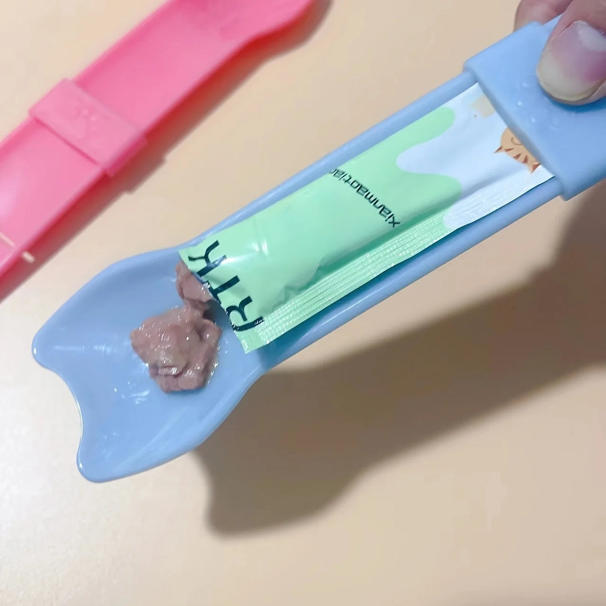Cat Strip Squeeze Spoon holding pet food packet, designed for easy feeding with a comfortable grip.