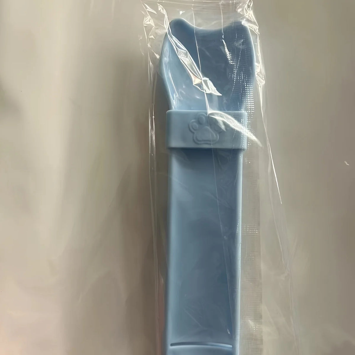 Cat Strip Squeeze Spoon holding pet food packet, designed for easy feeding with a comfortable grip.
